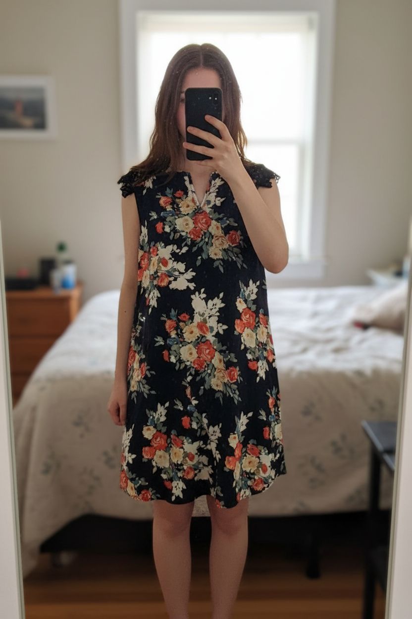 Abito estivo donna M - robe à fleurs été M in piedi, rivolto verso la fotocamera, in una camera da letto con luce soffusa e luce naturale che filtra dalla finestra.