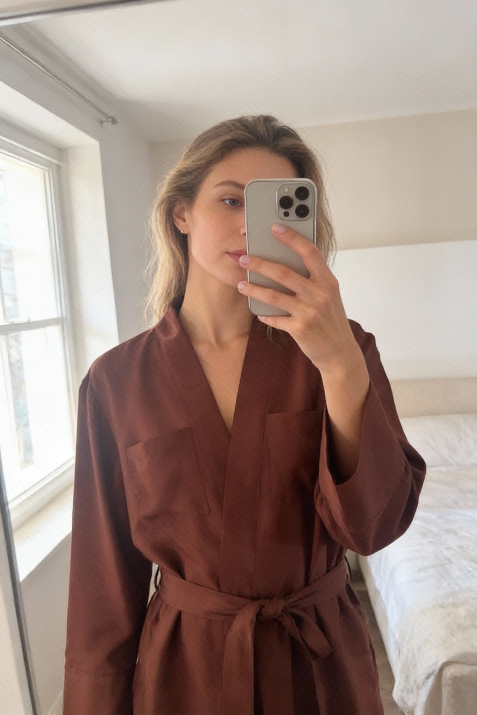 Robe soeur - terracota style japonais debout, face à la caméra, dans une chambre à la lumière douce, avec une lumière naturelle filtrant par la fenêtre.