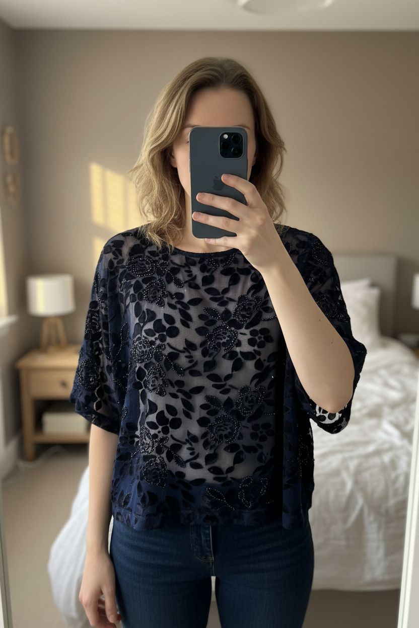 Blue and black top with sparkle standing straight facing the camera, in a softly lit bedroom setting, with gentle natural light filtering through a window.