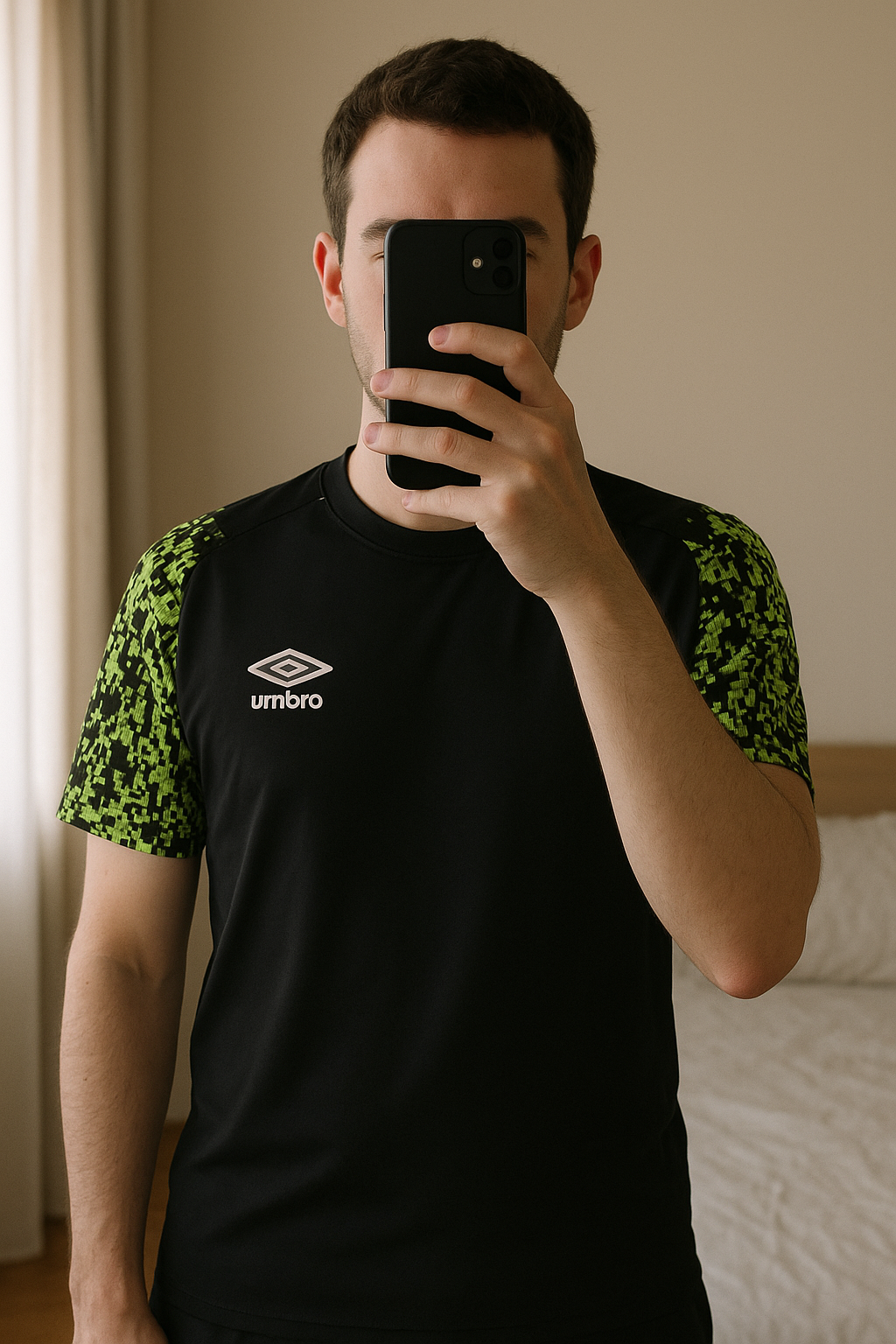Maillot Umbro debout, face à la caméra, dans une chambre à la lumière douce, avec une lumière naturelle filtrant par la fenêtre.