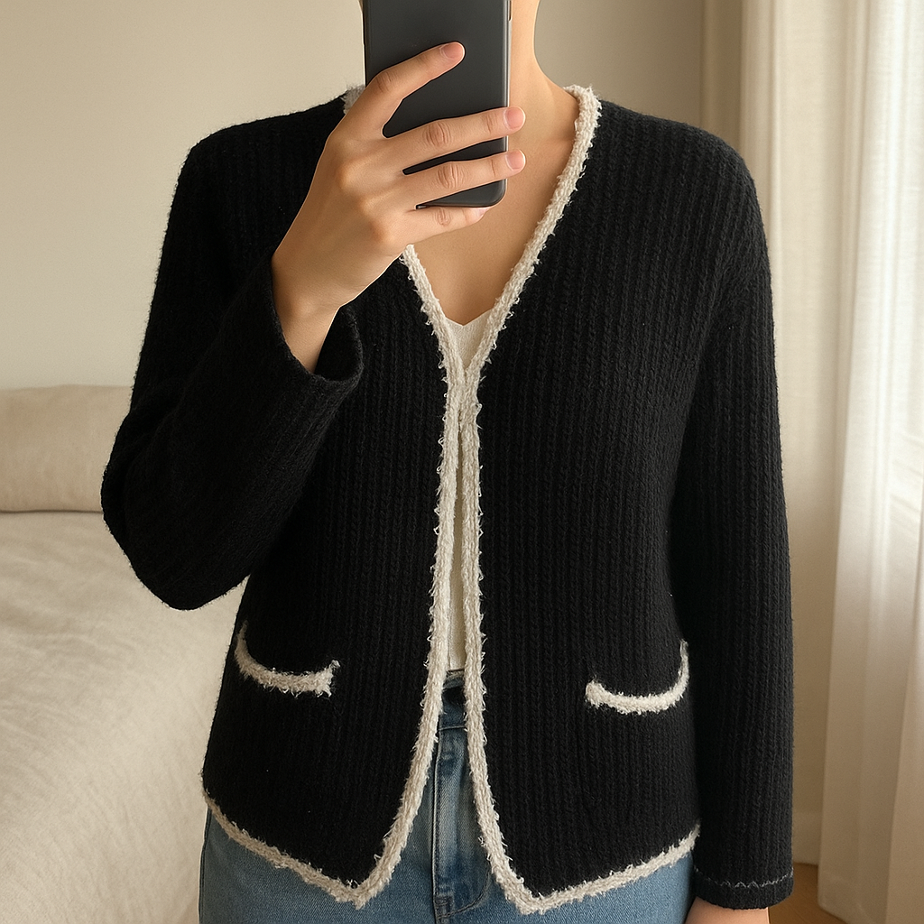 Gilet noir et blanc debout, face à la caméra, dans une chambre à la lumière douce, avec une lumière naturelle filtrant par la fenêtre.