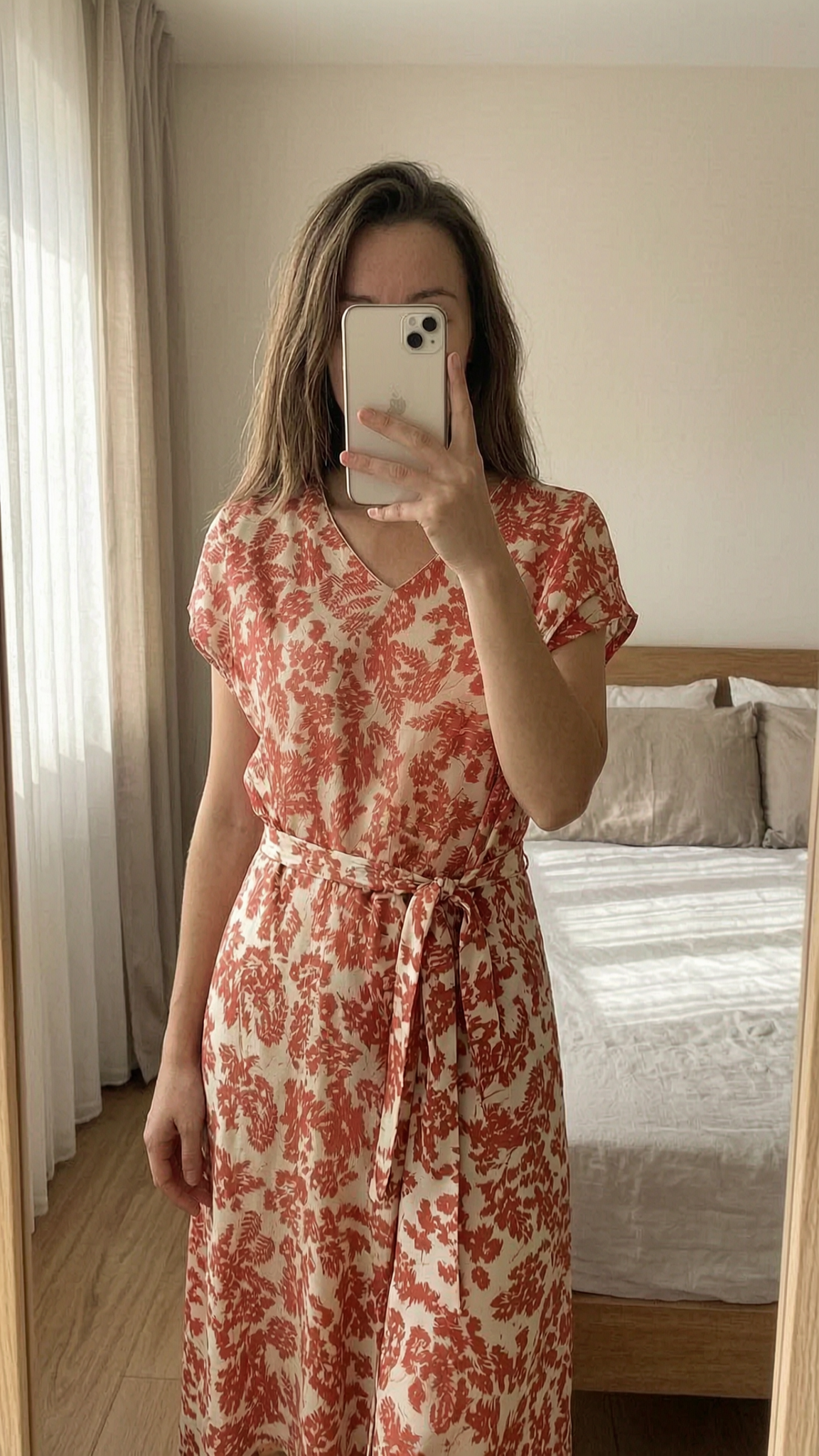 Robe courte debout, face à la caméra, dans une chambre à la lumière douce, avec une lumière naturelle filtrant par la fenêtre.