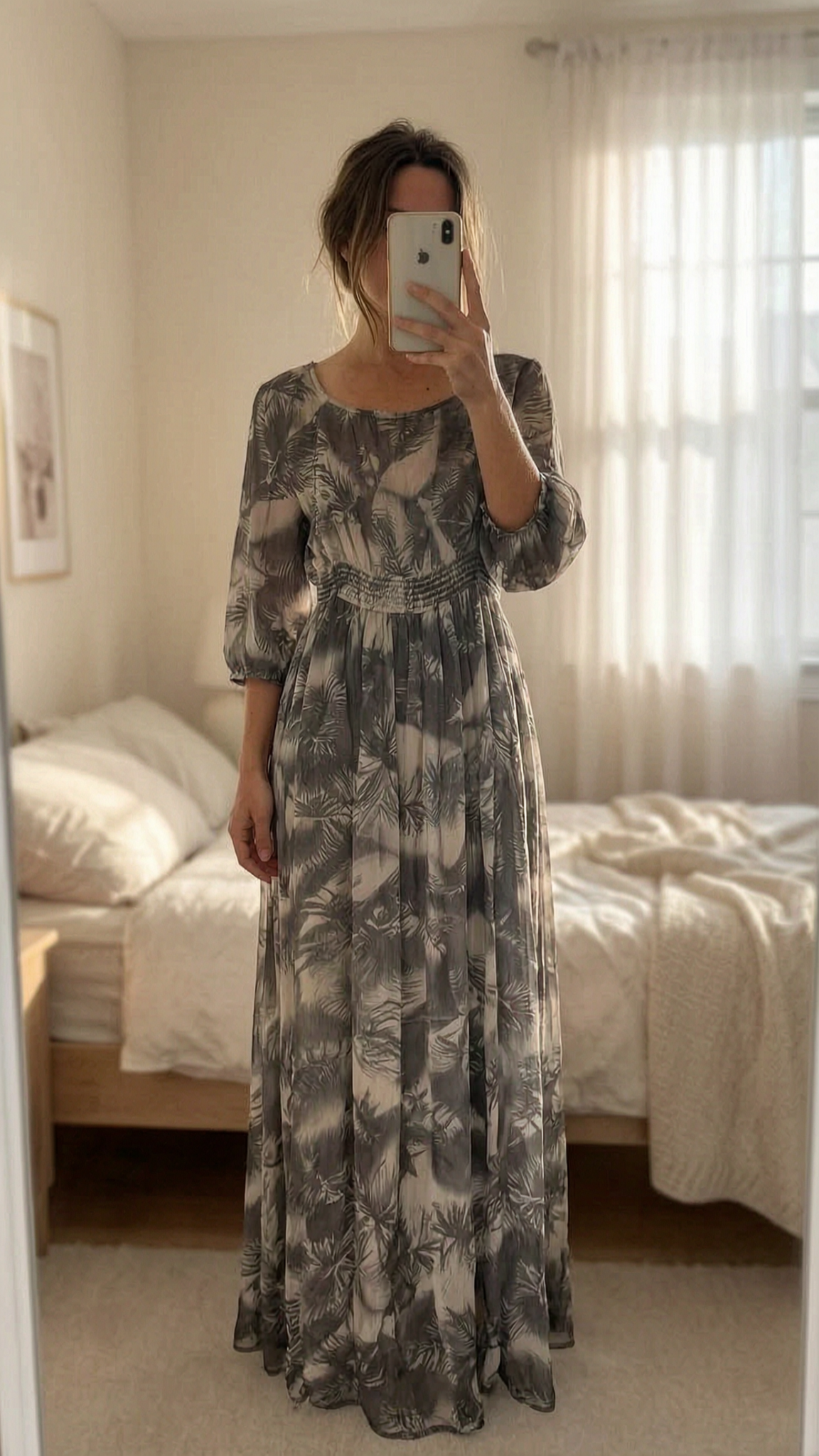 A person in H&M Grey Tropical Print Maxi Dress standing straight facing the camera, in a softly lit bedroom setting, with gentle natural light filtering through a window.