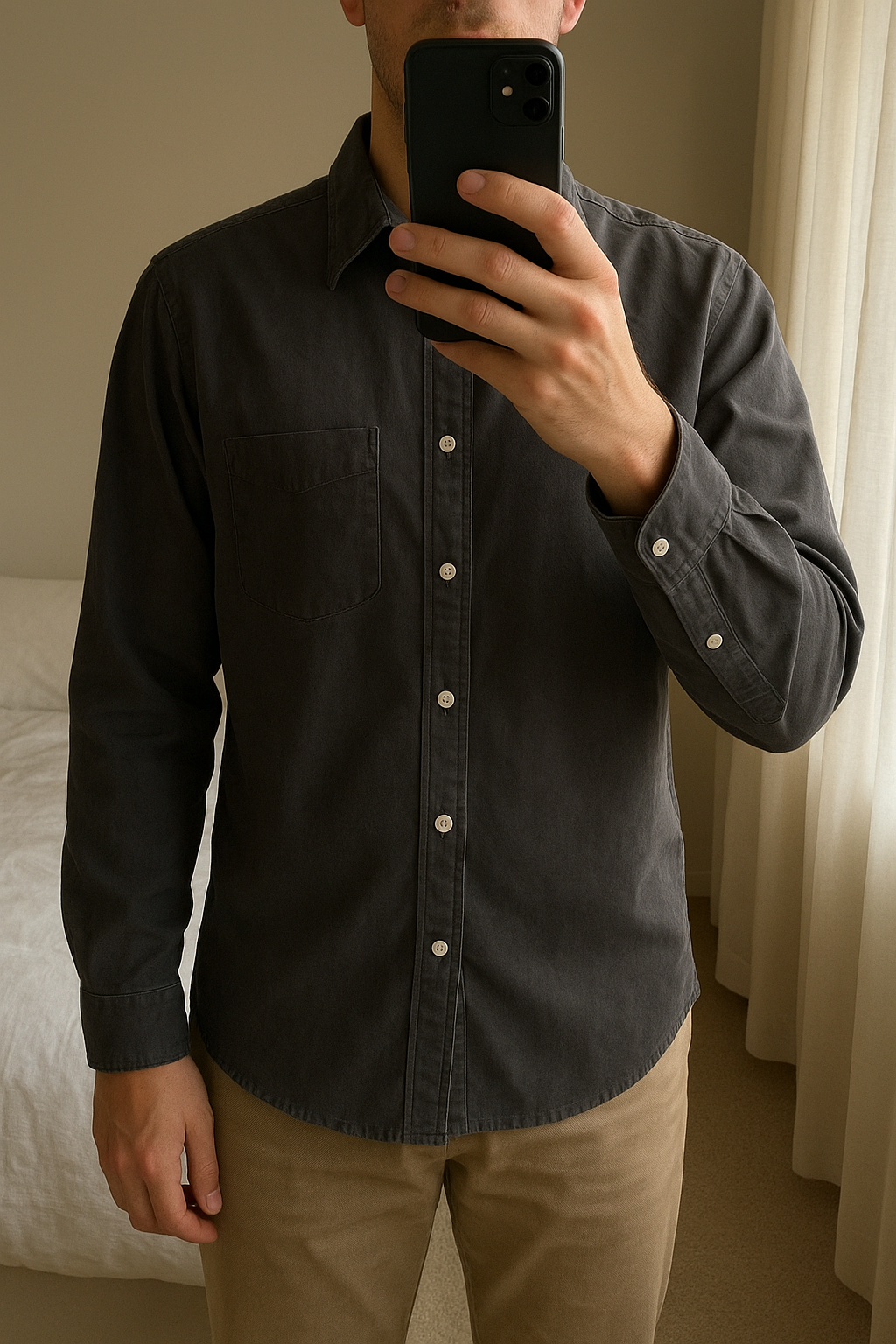 Chemise noire homme S - Camicia uomo Nero in piedi, rivolto verso la fotocamera, in una camera da letto con luce soffusa e luce naturale che filtra dalla finestra.