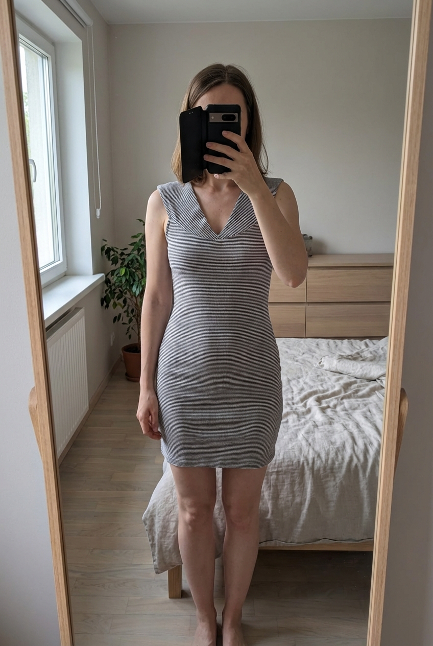 Robe courte Mango à rayures blanches et bleues Taille XS 💙 debout, face à la caméra, dans une chambre à la lumière douce, avec une lumière naturelle filtrant par la fenêtre.