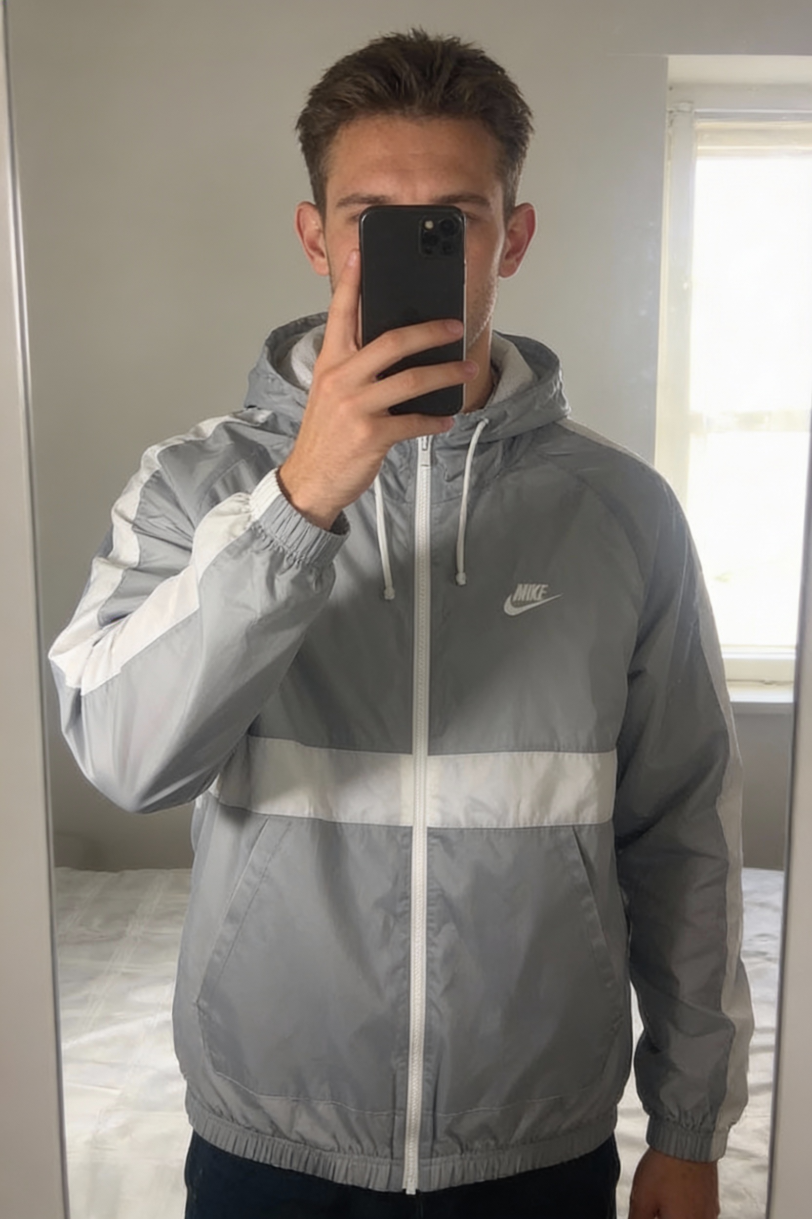 Nike Hoxton Suit Grey Windbreaker Jacket – Mesh Lined Hooded Zip Jacket Men’s Medium BNWT standing straight facing the camera, in a softly lit bedroom setting, with gentle natural light filtering through a window.