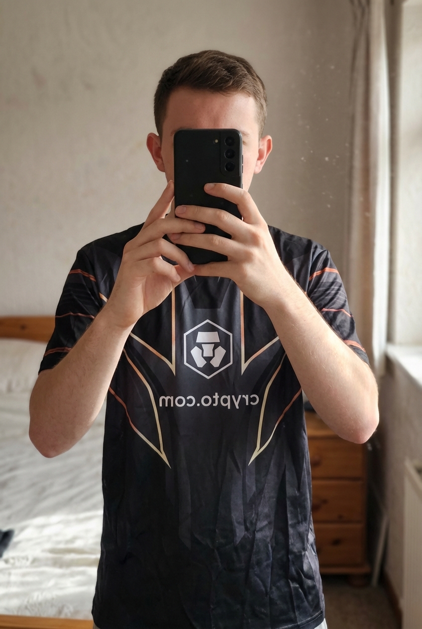 T-shirt debout, face à la caméra, dans une chambre à la lumière douce, avec une lumière naturelle filtrant par la fenêtre.