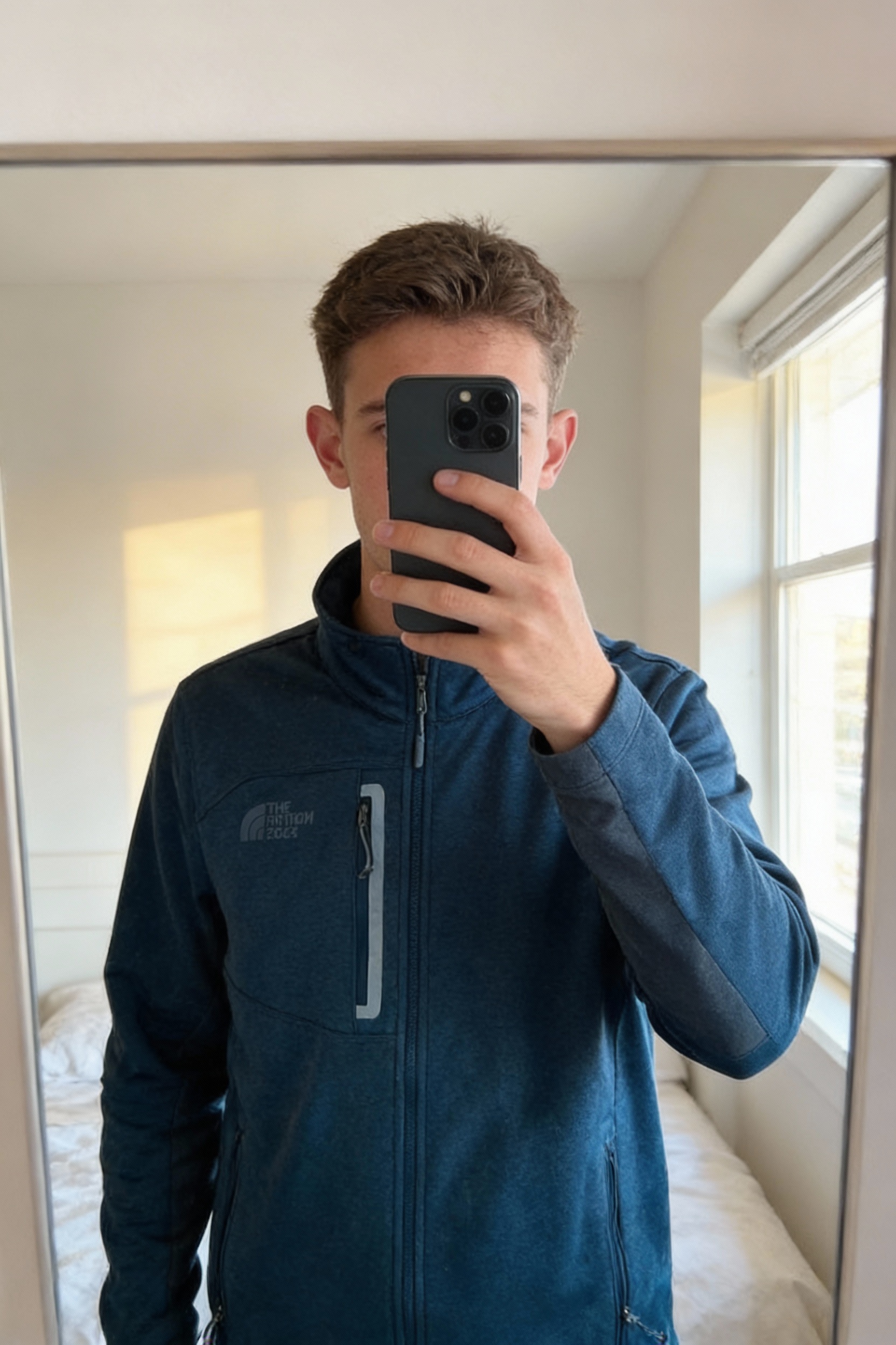 Magnifique polaire the north face bleu en excellent état ! 😃 debout, face à la caméra, dans une chambre à la lumière douce, avec une lumière naturelle filtrant par la fenêtre.