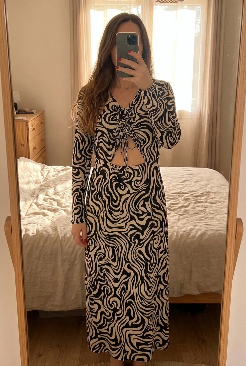 Robe longue noire et beige H&M taille 46 debout, face à la caméra, dans une chambre à la lumière douce, avec une lumière naturelle filtrant par la fenêtre.