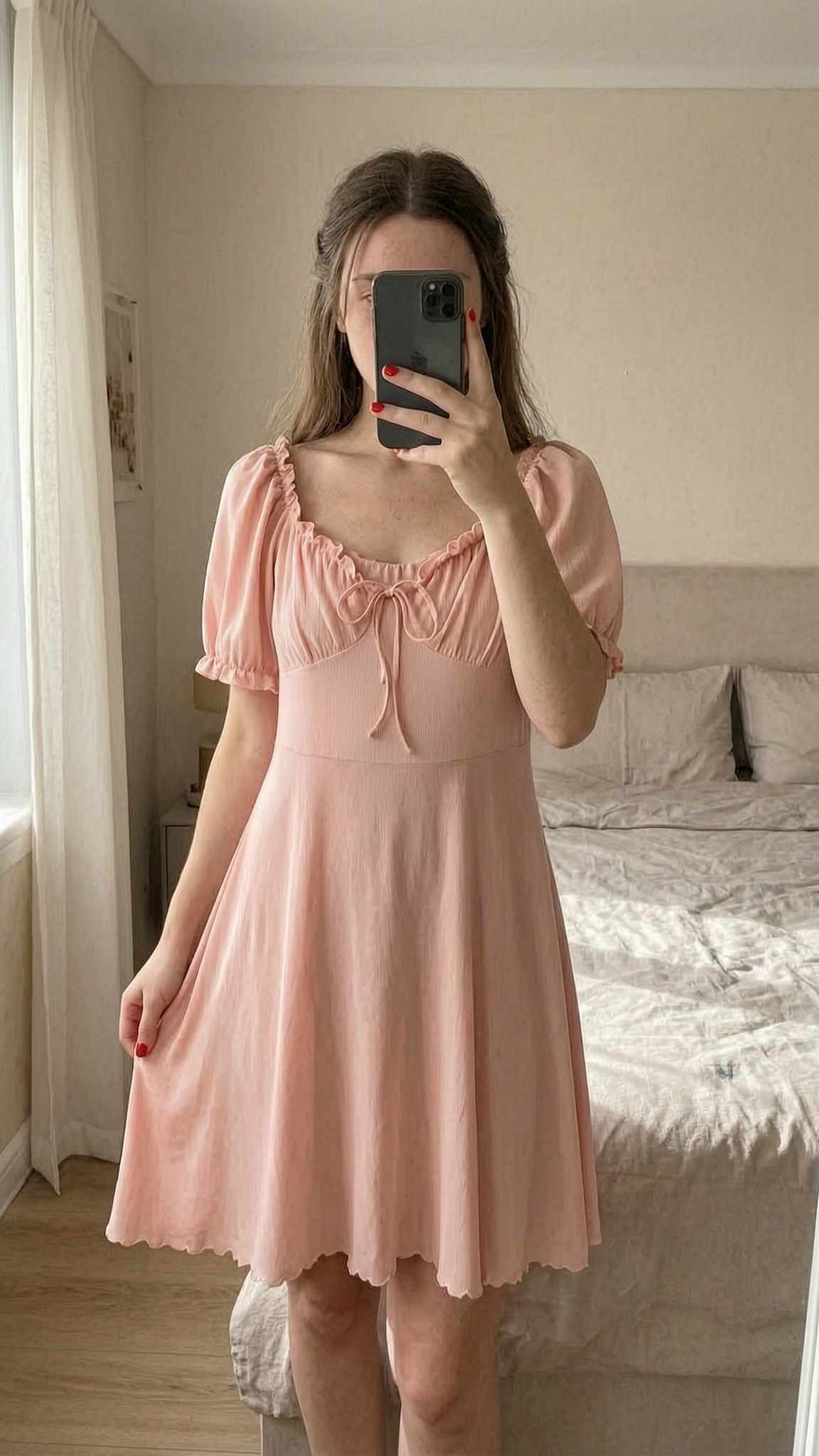 Robe rose légère femme lolita debout, face à la caméra, dans une chambre à la lumière douce, avec une lumière naturelle filtrant par la fenêtre.