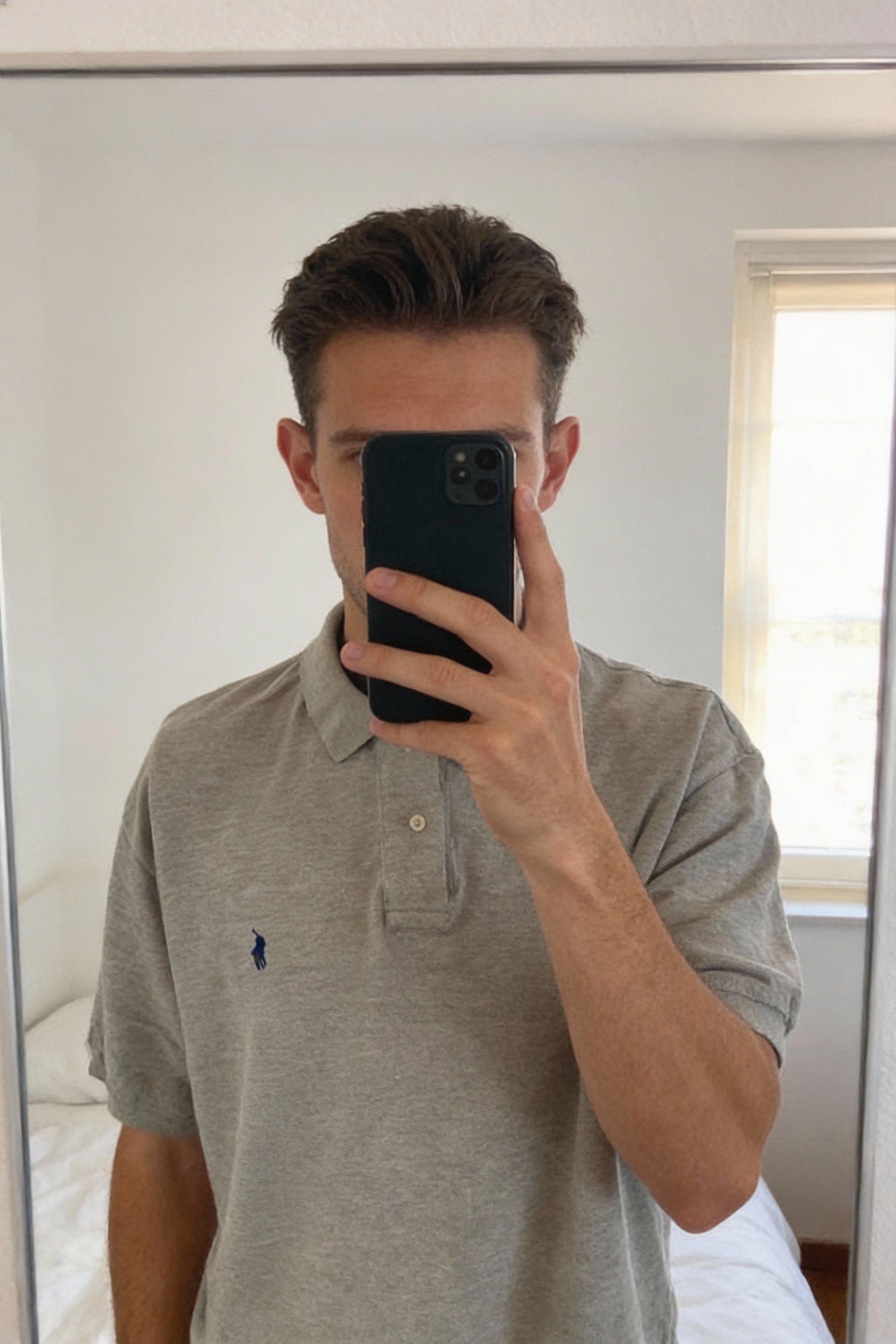 Ralph Lauren - Polo - Taille M debout, face à la caméra, dans une chambre à la lumière douce, avec une lumière naturelle filtrant par la fenêtre.