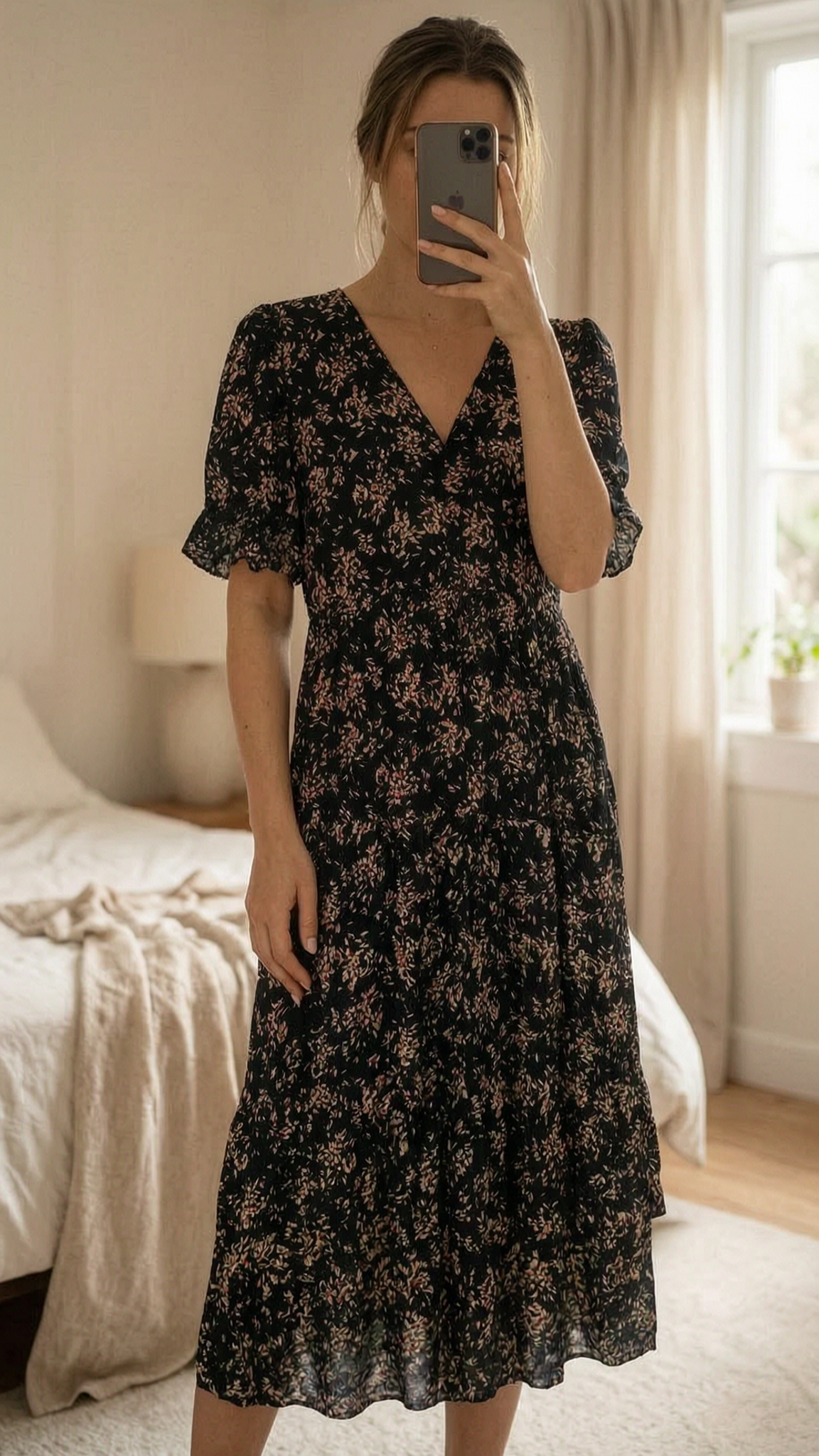 Robe longue fleurie ba&sh T2 – noire bohème fluide de pie, mirando a la cámara, en un dormitorio con luz suave y natural filtrándose por la ventana.