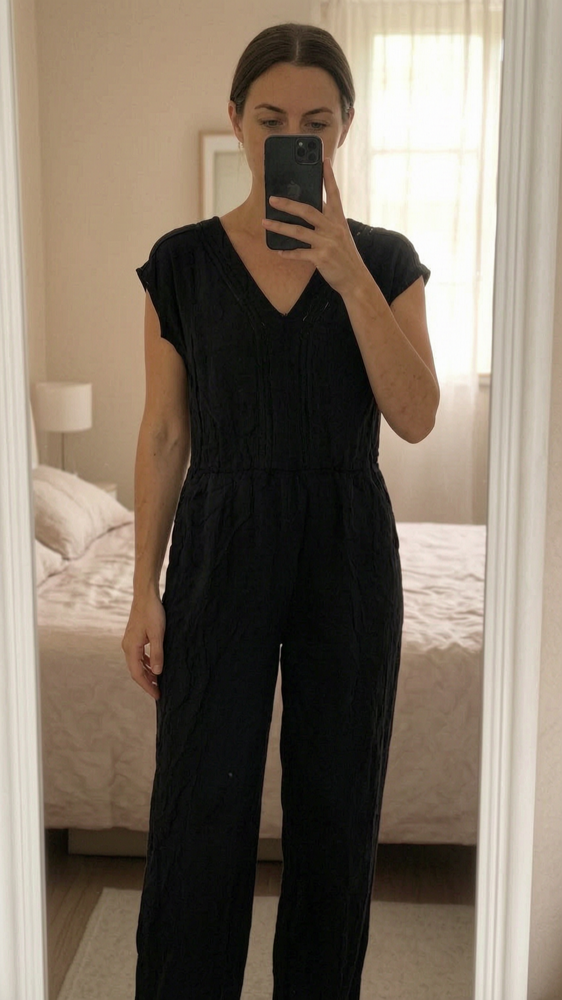 Combinaison debout, face à la caméra, dans une chambre à la lumière douce, avec une lumière naturelle filtrant par la fenêtre.