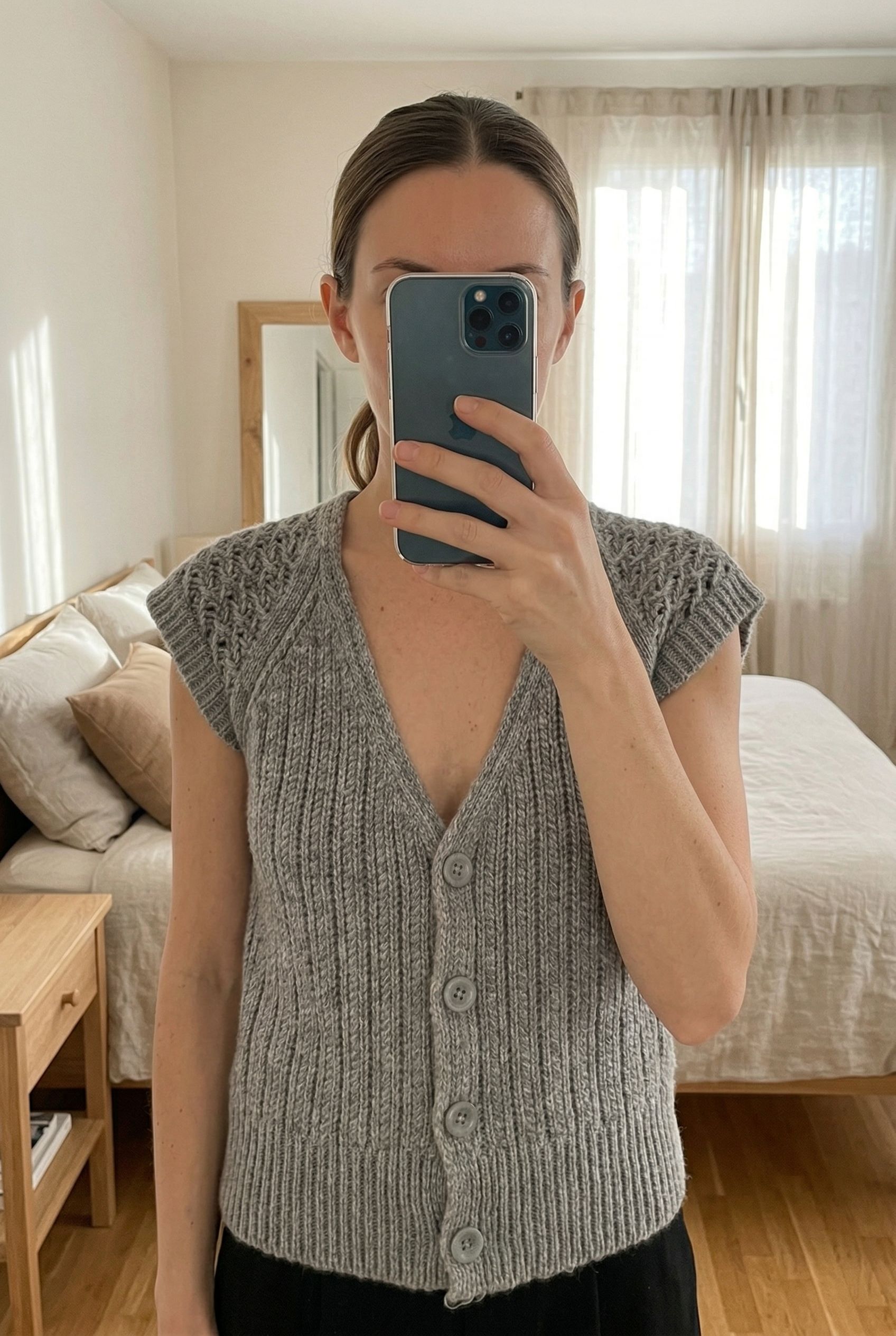 Gilet Gérard Darel S alpaga debout, face à la caméra, dans une chambre à la lumière douce, avec une lumière naturelle filtrant par la fenêtre.