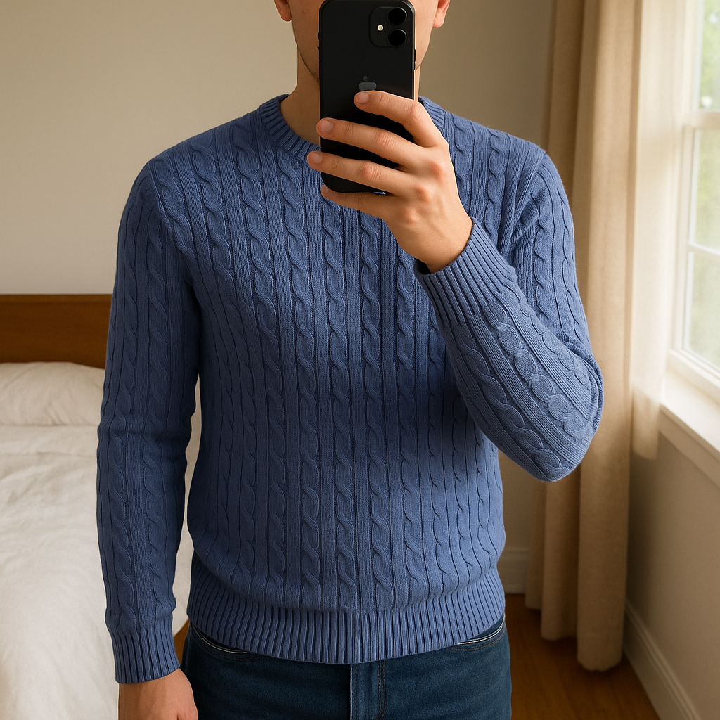 Pull torsadé Tommy Hilfiger homme XXL – bleu sans logo debout, face à la caméra, dans une chambre à la lumière douce, avec une lumière naturelle filtrant par la fenêtre.
