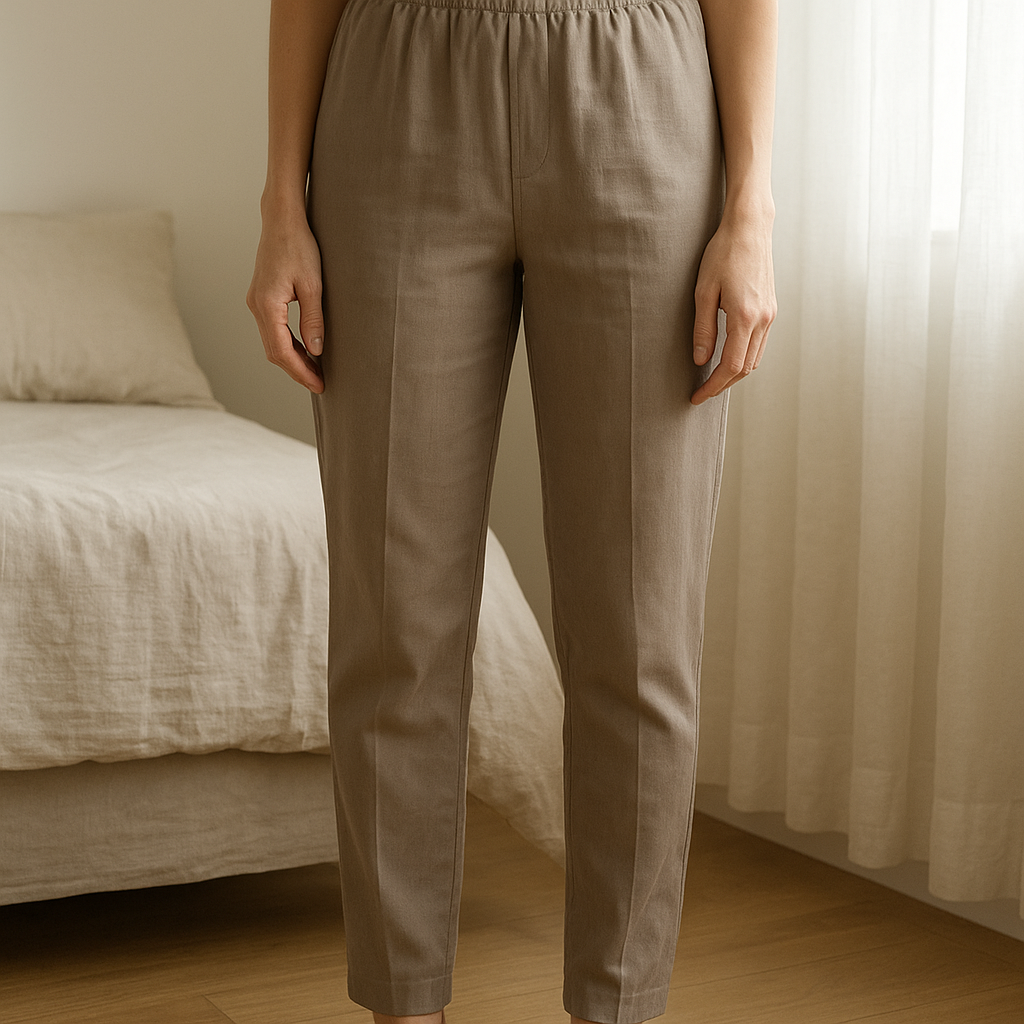 Women's trouser standing straight facing the camera, in a softly lit bedroom setting, with gentle natural light filtering through a window.
