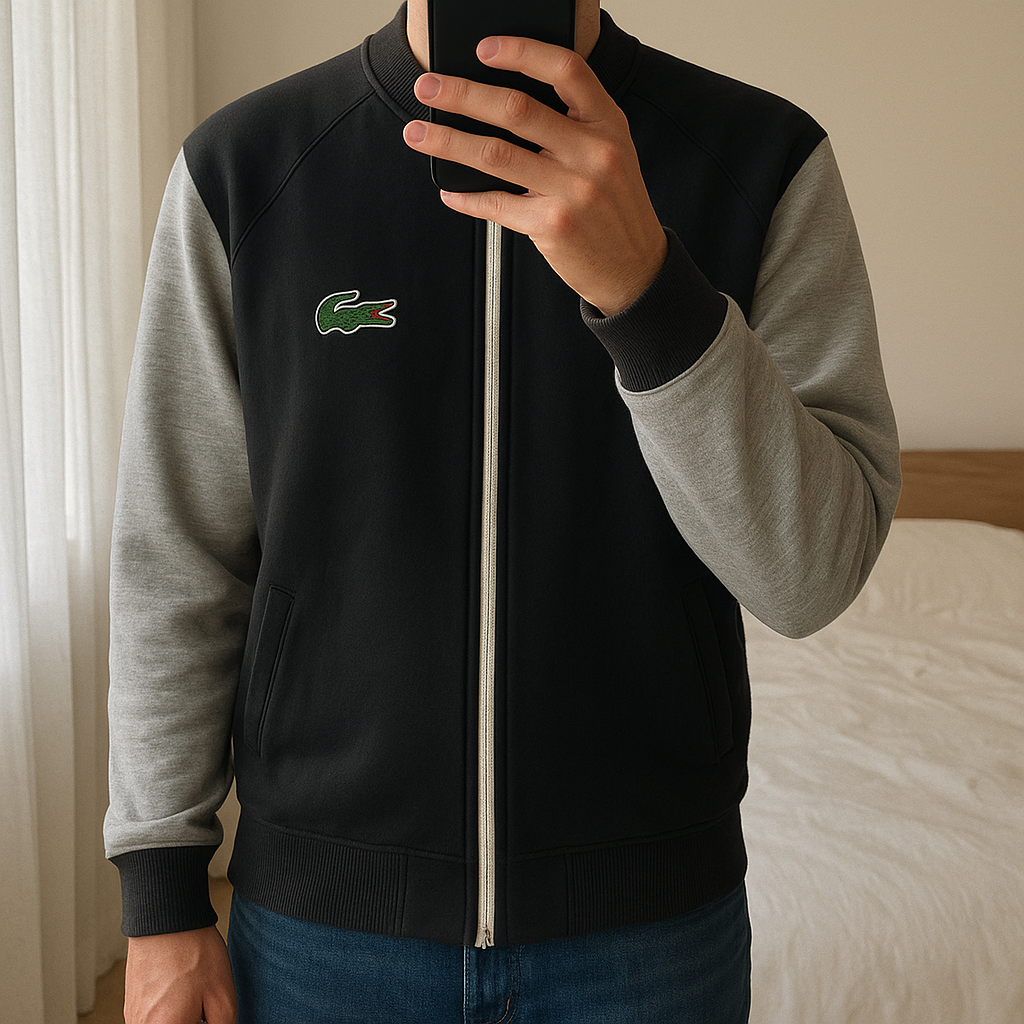 Veste Lacoste debout, face à la caméra, dans une chambre à la lumière douce, avec une lumière naturelle filtrant par la fenêtre.