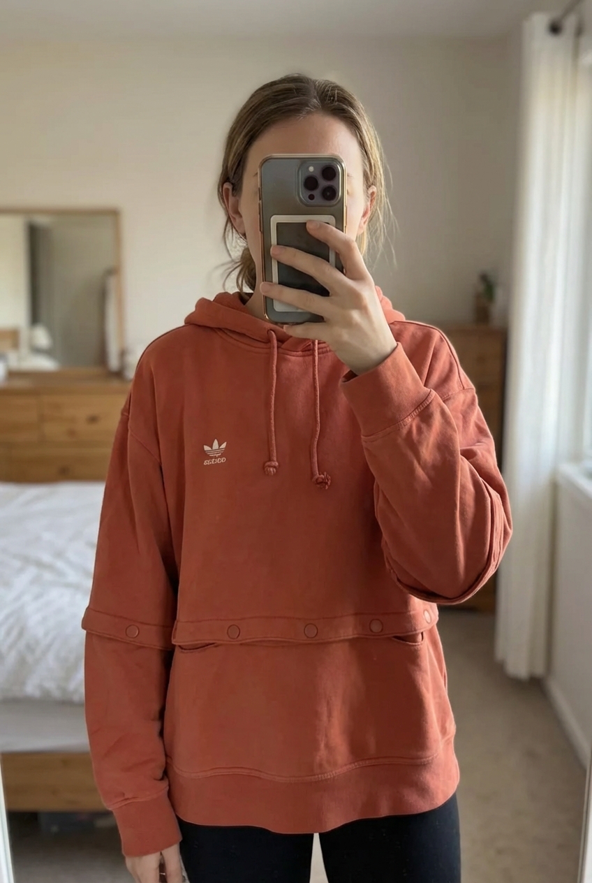 Sweat à capuche adidas M - felpa adidas Donna M in piedi, rivolto verso la fotocamera, in una camera da letto con luce soffusa e luce naturale che filtra dalla finestra.