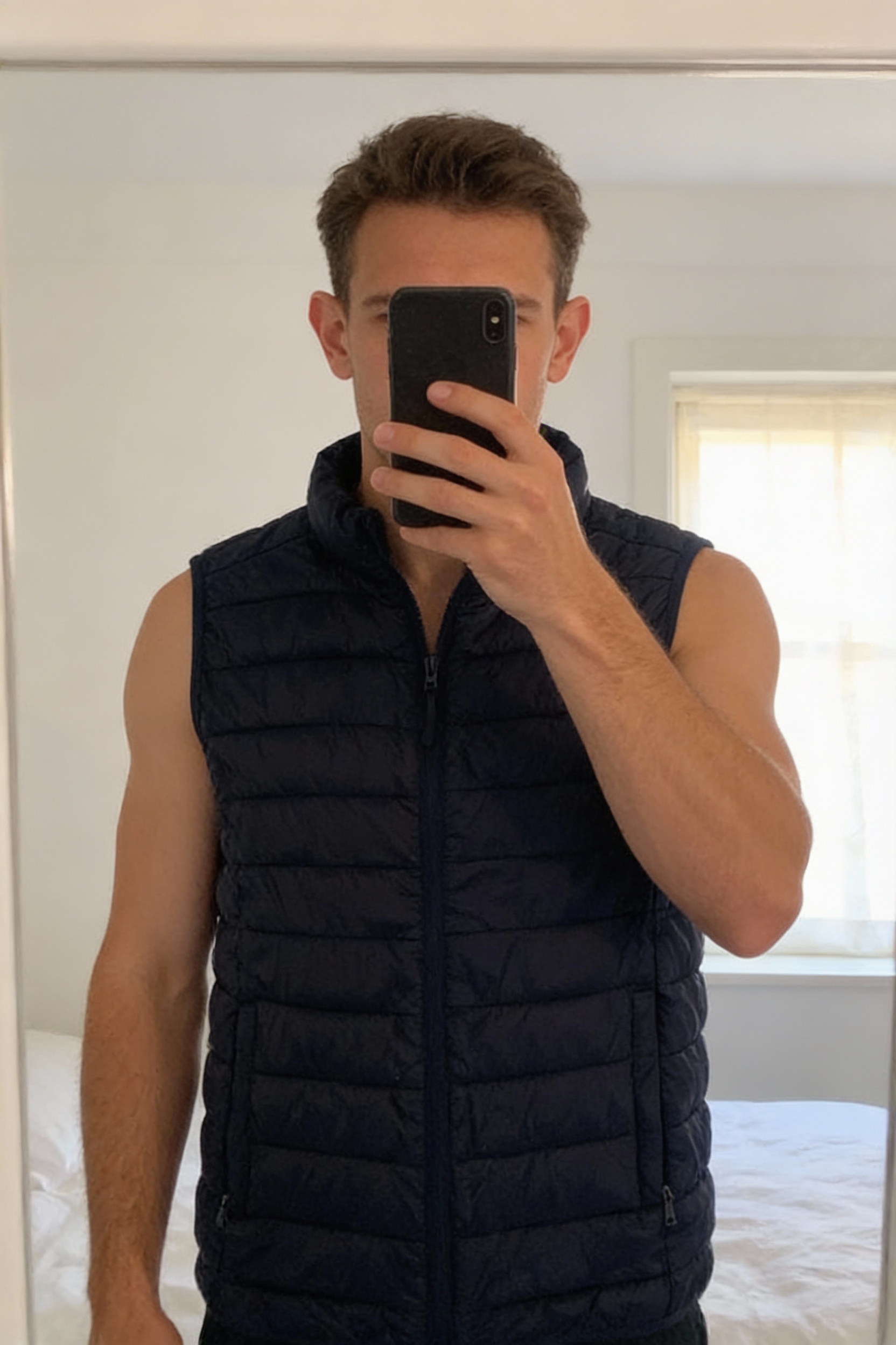 Workout Mens size M ultra lightweight navy puffer/running gilet body warmer with two inside pockets standing straight facing the camera, in a softly lit bedroom setting, with gentle natural light filtering through a window.