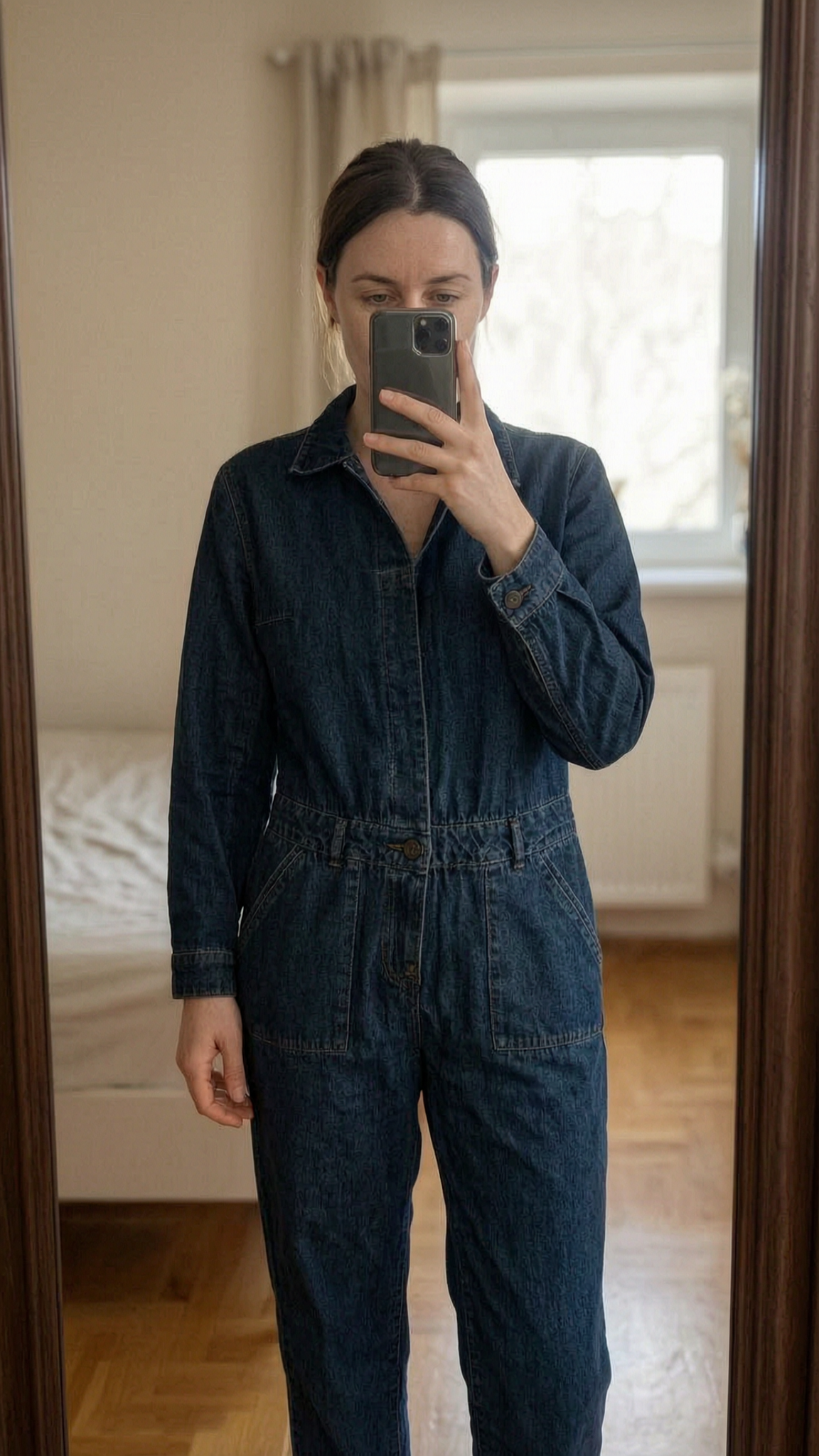 Magnifique combipantalon S - tute jumpsuit Donna S in piedi, rivolto verso la fotocamera, in una camera da letto con luce soffusa e luce naturale che filtra dalla finestra.