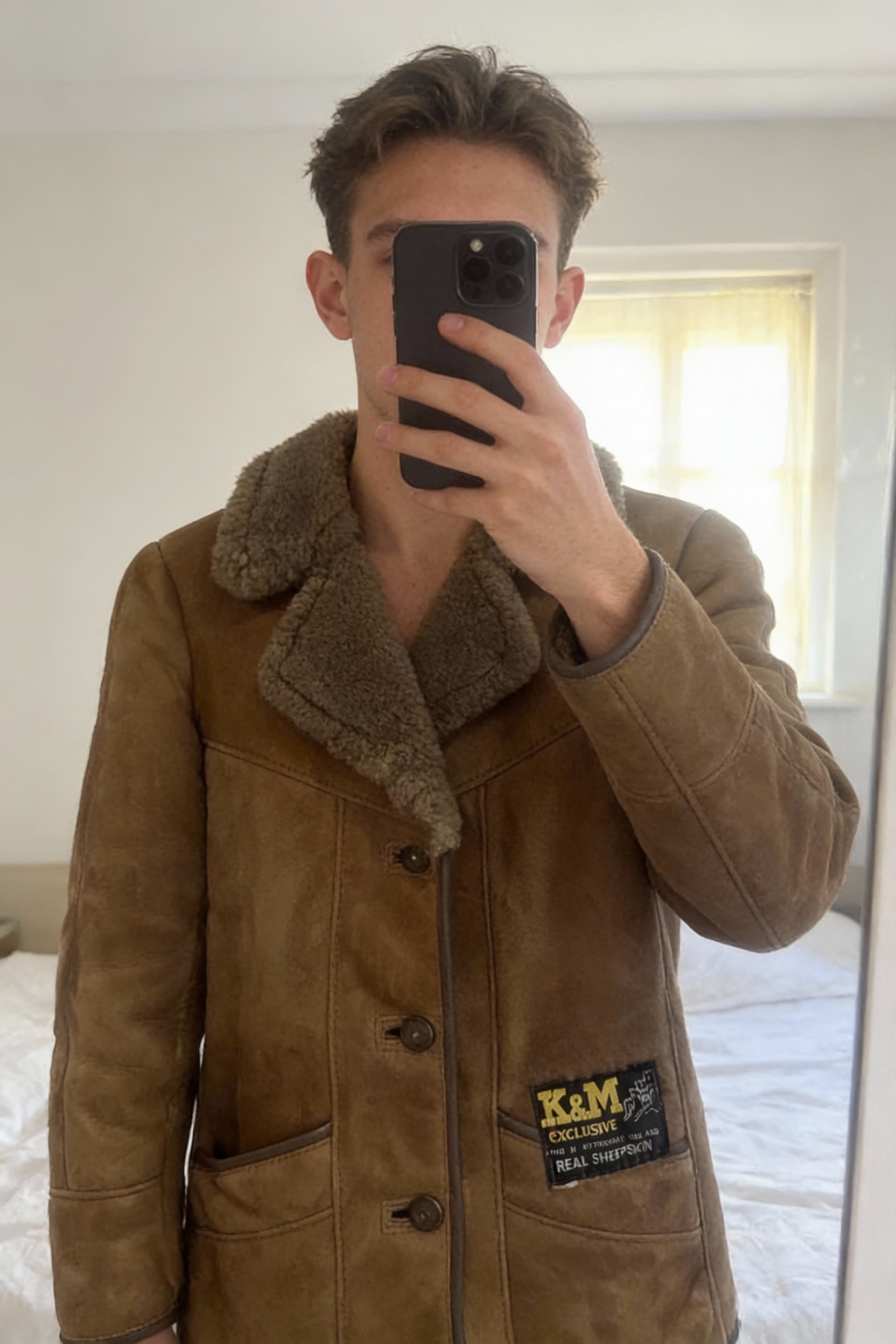 Vintage sherling jacket standing straight facing the camera, in a softly lit bedroom setting, with gentle natural light filtering through a window.