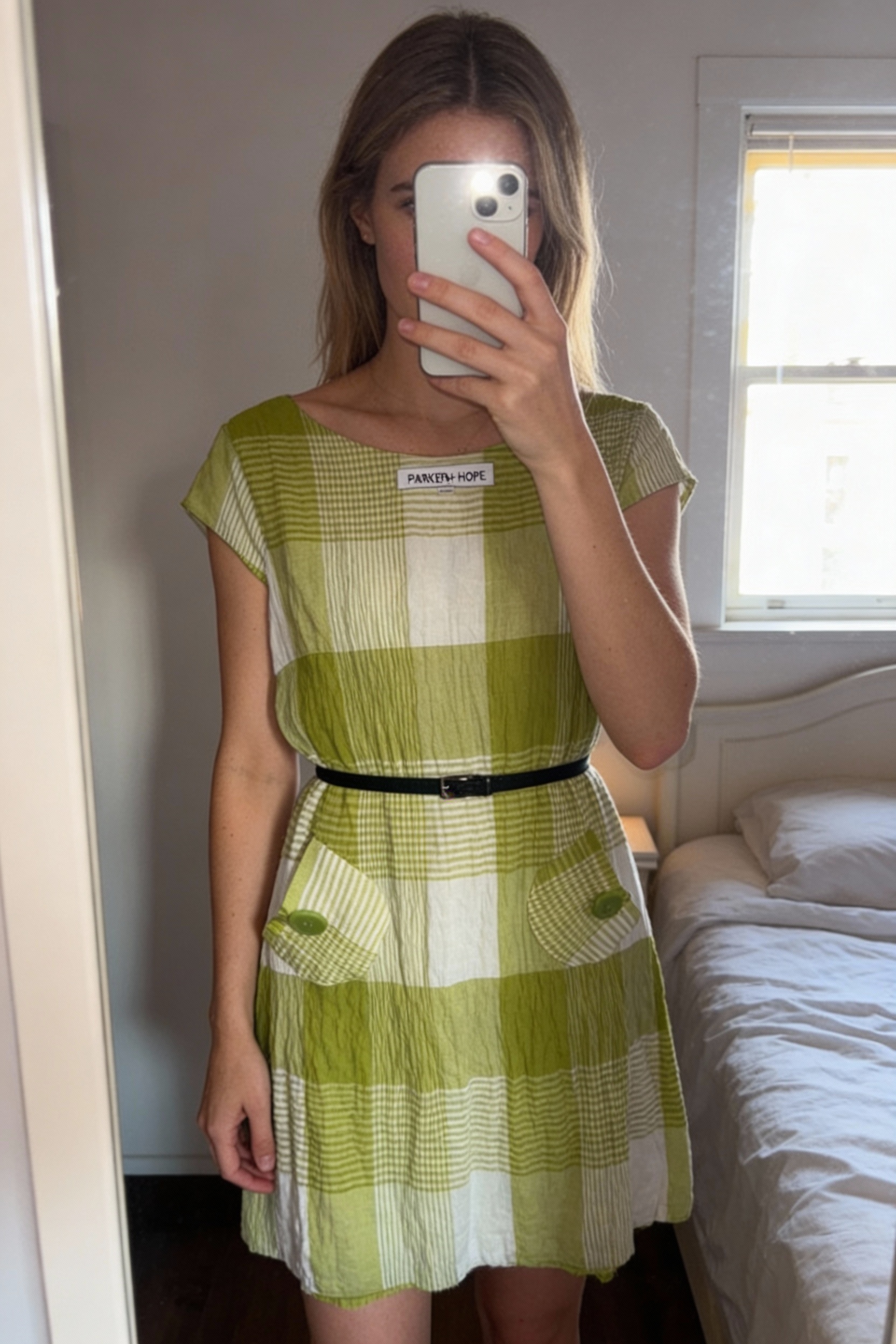 Green & white check linen blend dress – Annalee + Hope standing straight facing the camera, in a softly lit bedroom setting, with gentle natural light filtering through a window.