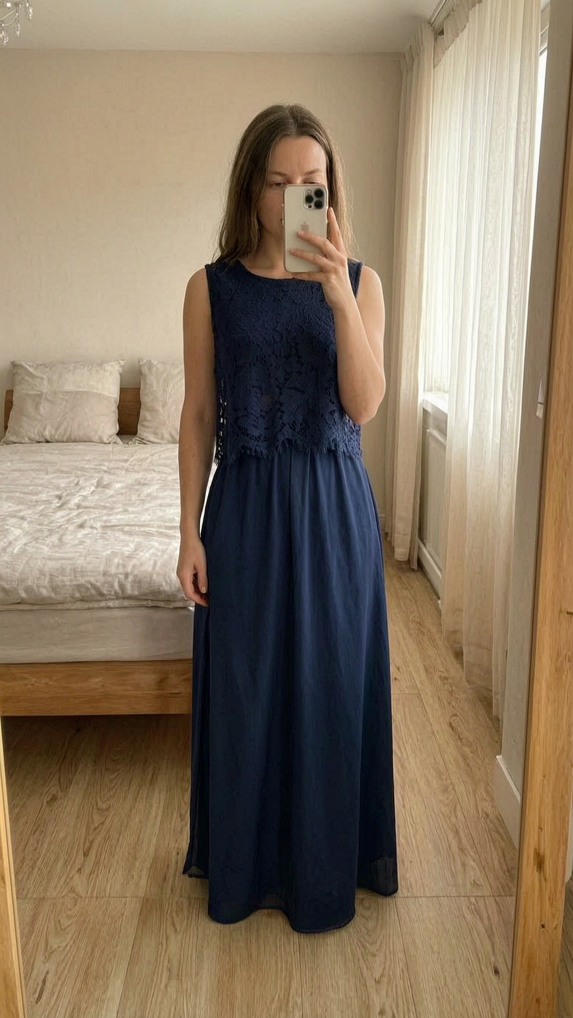 Robe longue habillée, bleu-marine, neuve ! debout, face à la caméra, dans une chambre à la lumière douce, avec une lumière naturelle filtrant par la fenêtre.